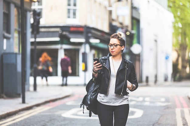 Girl walking down the street with her phone.