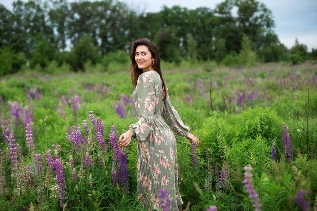 girl walking on field summer with wildflowers woman in dress in blooming lupine field