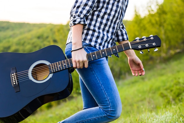 Girl walking in the field with a guitar in hand