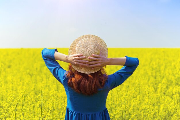 Girl walking in a field of yellow rapeseed