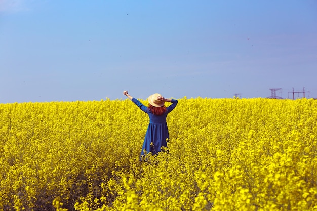 Girl walking in a field of yellow rapeseed