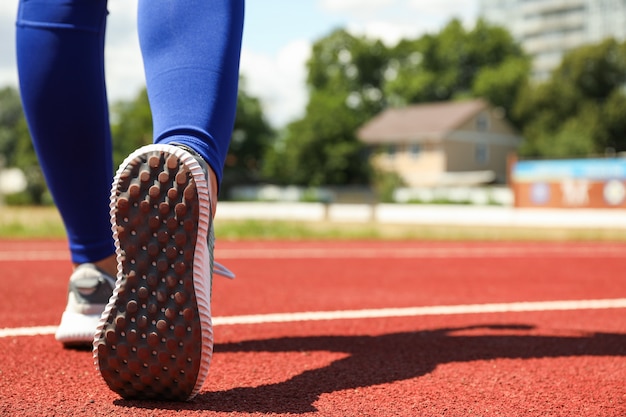 Girl walking on red athletic track, space for text