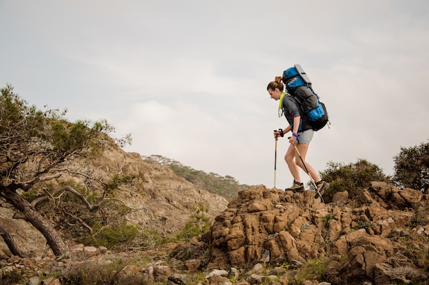 Girl walking on the rocks with hiking backpack