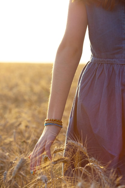 Girl walking through the field and touching a wheat with her hand