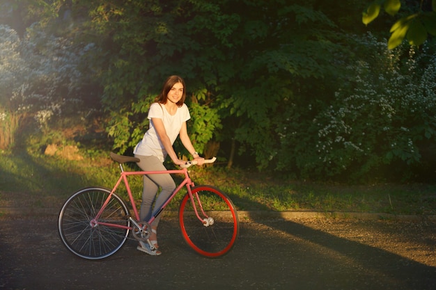 Девушка гуляет с велосипедом на закате