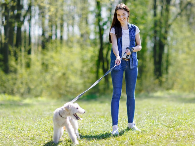 Girl walking with a dog on a leash in a summer park