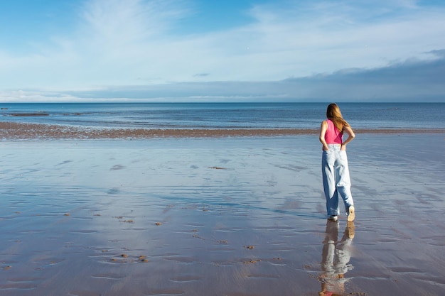 A girl walks along the coast of the North Sea in the UK