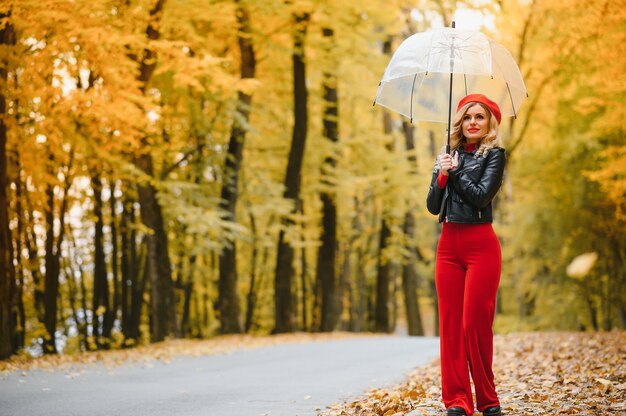 A girl walks in the autumn park under an umbrella