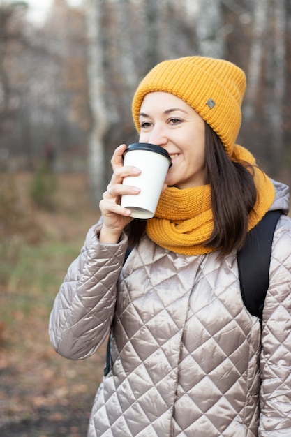 Girl walks in the autumn park with a cup of coffee. High quality photo