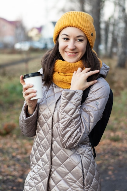 Girl walks in the autumn park with a cup of coffee