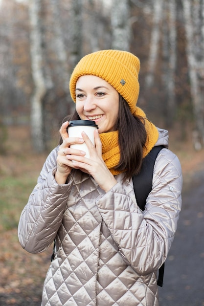 女の子は一杯のコーヒーと秋の公園を歩く