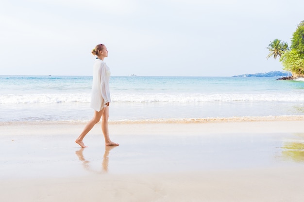 La ragazza cammina sulla spiaggia e nell'acqua