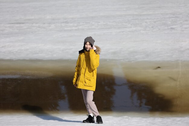 A girl walks by a melting river