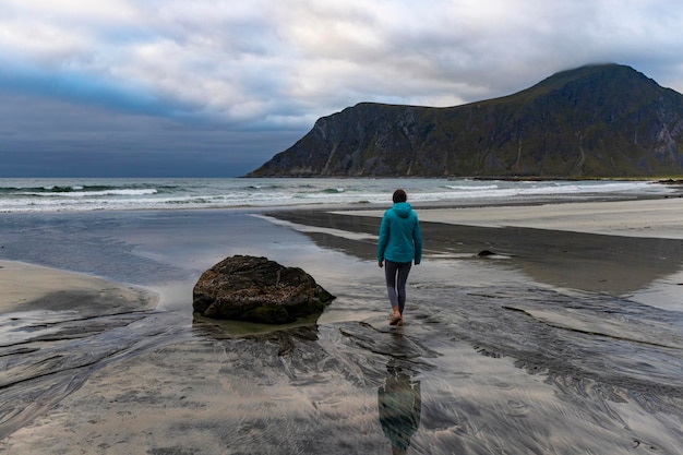 女の子が有名なサーファーのビーチを歩く - ノルウェーのロフォーテン諸島の uttakleiv ビーチ