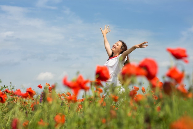 Girl walks in a field of poppies