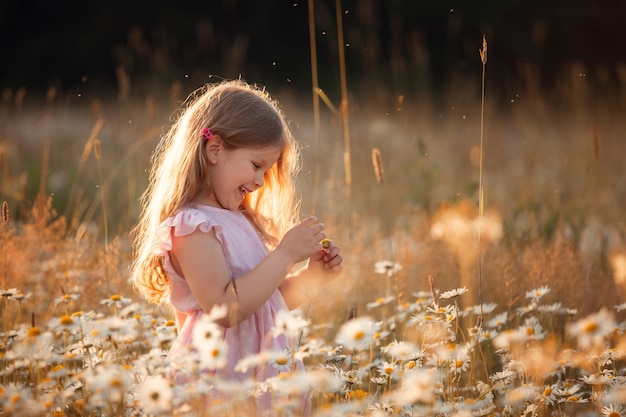 A girl walks in a field with daisies