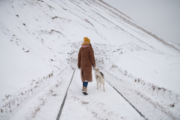 A girl walks her dog through the winter forest
