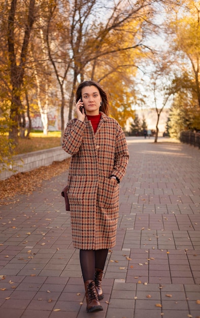 A girl walks in the park and talks on the phone business concept