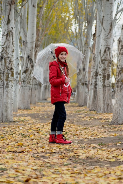 A girl walks and plays with a transparent umbrella in the park Autumn Atmosther