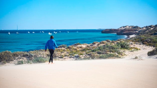 girl walks on sand dunes in coral bay overlooking ningaloo reef, western australia