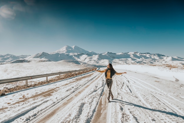 Elbrus 산이 내려다 보이는 눈 덮인 길을 걷는 소녀.