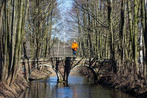 Girl walks in the spring in the orange jacket and orange handbag