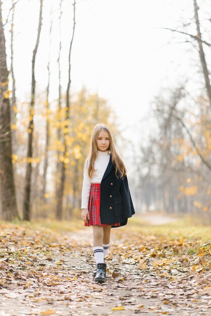 A girl walks through the autumn forest after school