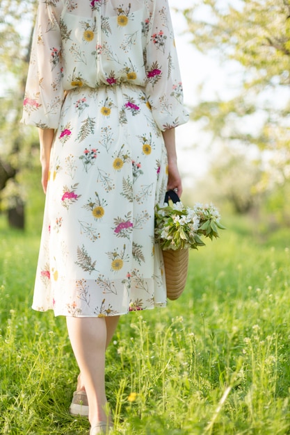 Девушка гуляет по весеннему зеленому парку, наслаждаясь цветущей природой