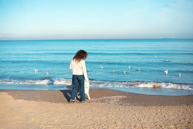 Девушка гуляет с собакой на пляже.