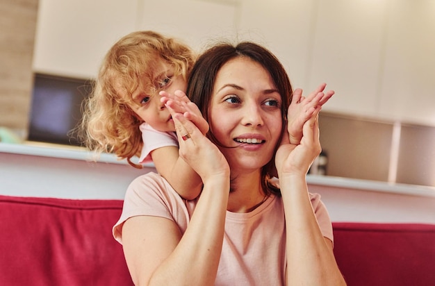 Girl wanna have fun Young mother with her little daughter in casual clothes together indoors at home