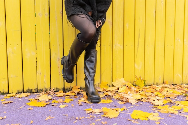 Photo a girl in warm boots poses against a background of fallen foliage