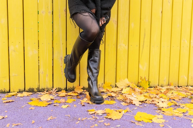 Photo a girl in warm boots poses against a background of fallen foliage