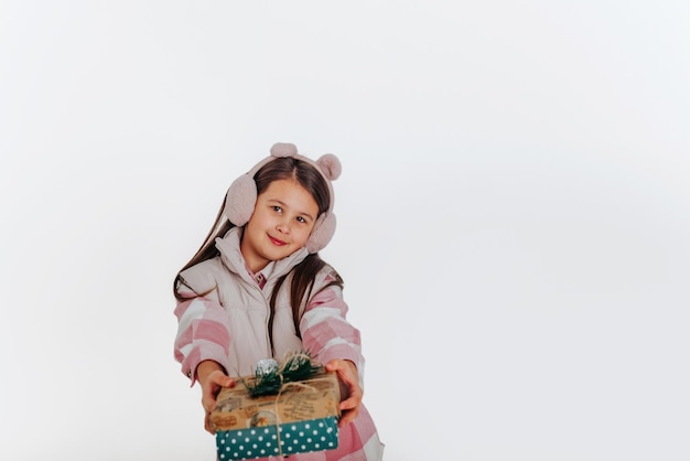 a girl in warm clothes presenting a gift on the white background Space for text