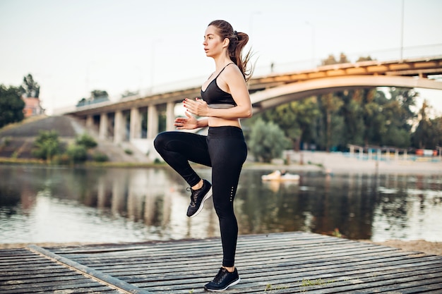 Girl warming up on wooden platform on riverbank