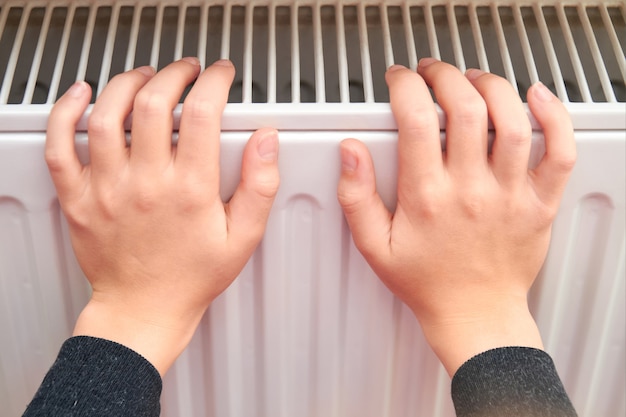 Girl warms her hands on the radiator