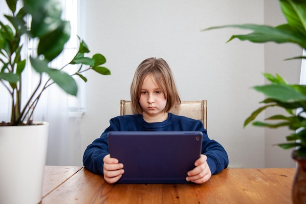 A girl watches a movie on a tablet at a table