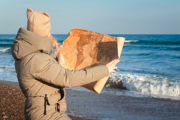 冬の晴れた日に海沿いの地図を見ている女の子