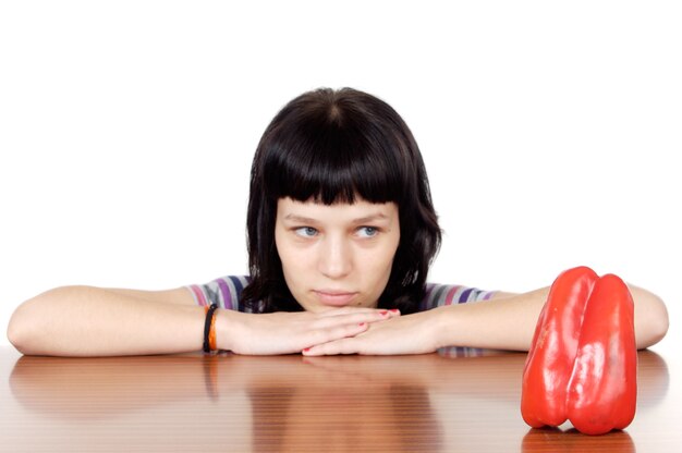 Girl watching a red pepper over white background 