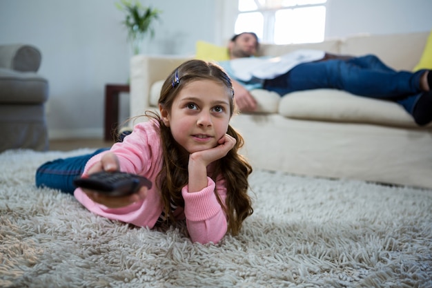 リビングルームの敷物の上に横たわるテレビを見ている女の子