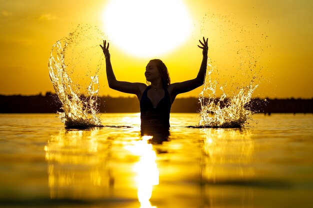 Photo girl in the water at sunset