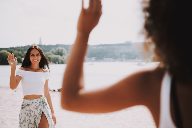 Ragazza che ondeggiano gli amici di saluto della mano su sandy beach