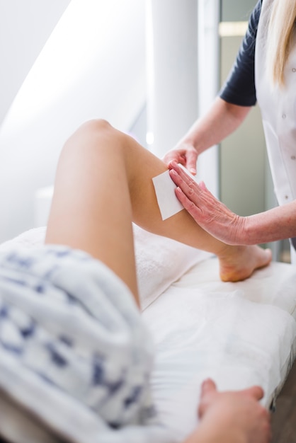 Photo girl waxing on her legs in a beauty salon