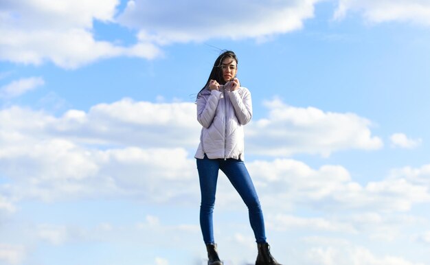 Girl wear jacket in city street. Stylish fashion model outdoor. People freedom style. Winter Warm Clothing. girl wearing casual jeans clothes. enjoys sunny day and blue sky. beauty and fashion.