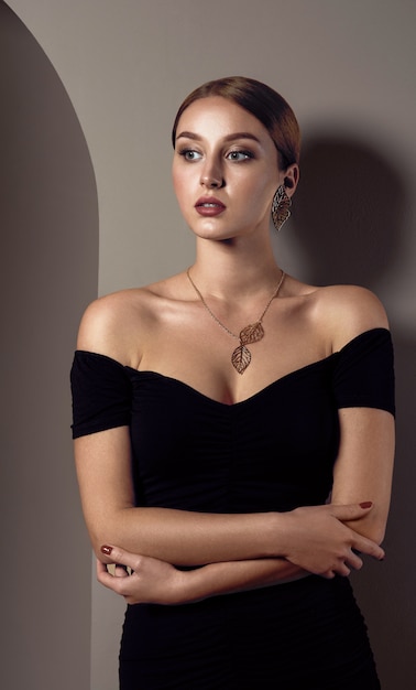 Girl wearing black off shoulders dress and leaves shape golden necklace