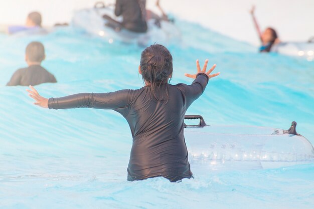 黒い水着を着て透明なラバーリングで海水を泳ぐ少女。