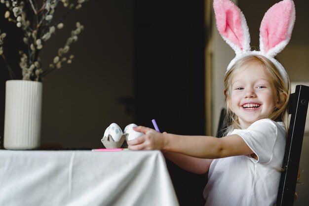 Photo a girl wearing bunny ears sits at a table with a pink table cloth.