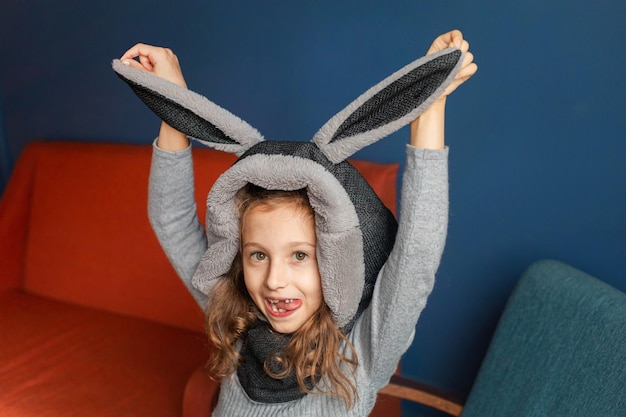 Girl wearing a bunny hat sticking her tongue out holding two ears up