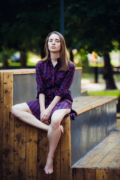 Ragazza che porta vestito a scacchi che si siede nello skatepark