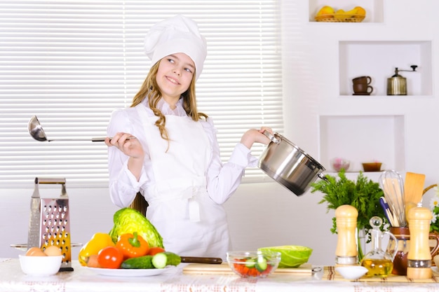 Ragazza che indossa l'uniforme del cuoco unico che cucina sulla cucina