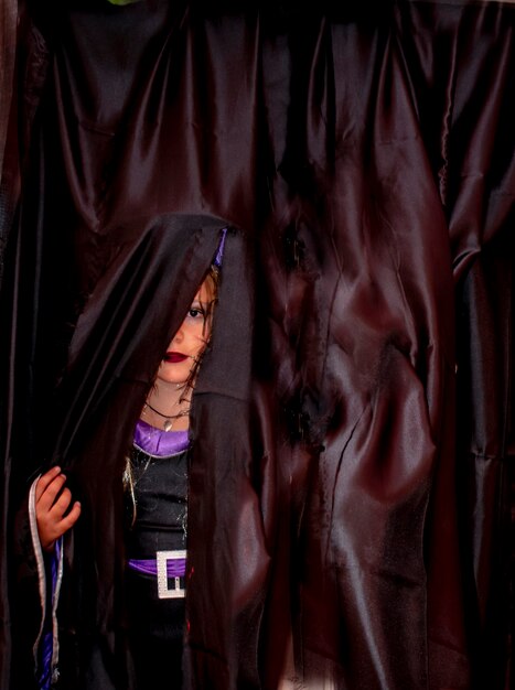 Photo girl wearing costume standing behind curtain during halloween